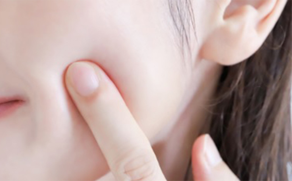 손가락으로 매끄러운 볼 피부를 가리키는 클로즈업 사진