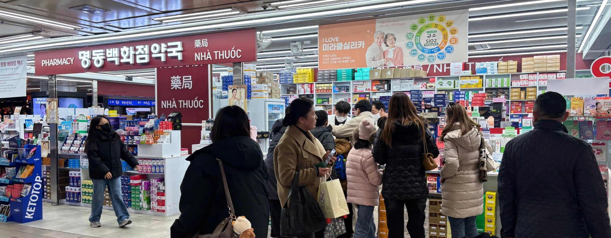 Foreign tourists looking at K-beauty products at a pharmacy in Seoul