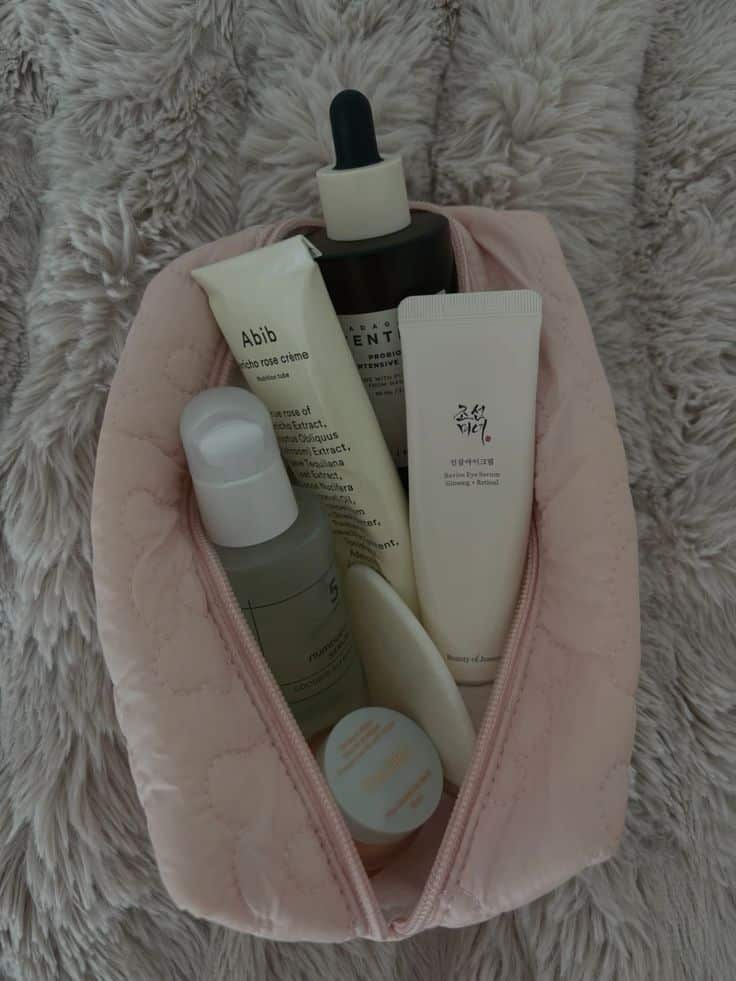 K-beauty sample serums, creams, and essences arranged in a pink pouch