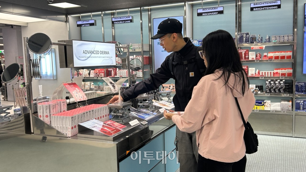 올리브영 매장 내에서 외국인 관광객이 스킨케어 제품을 살펴보고 있는 장면
