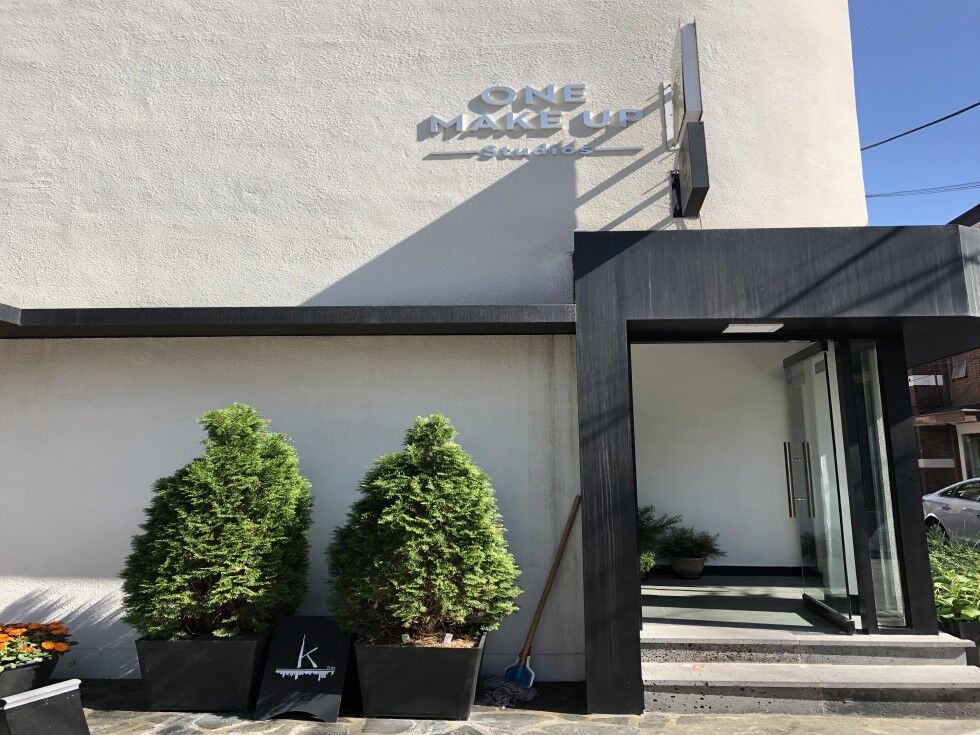 The white exterior of a makeup studio located in Hongdae Yeonnam-dong shows a logo reading 'One Makeup Studio,' and green plants are planted in the garden