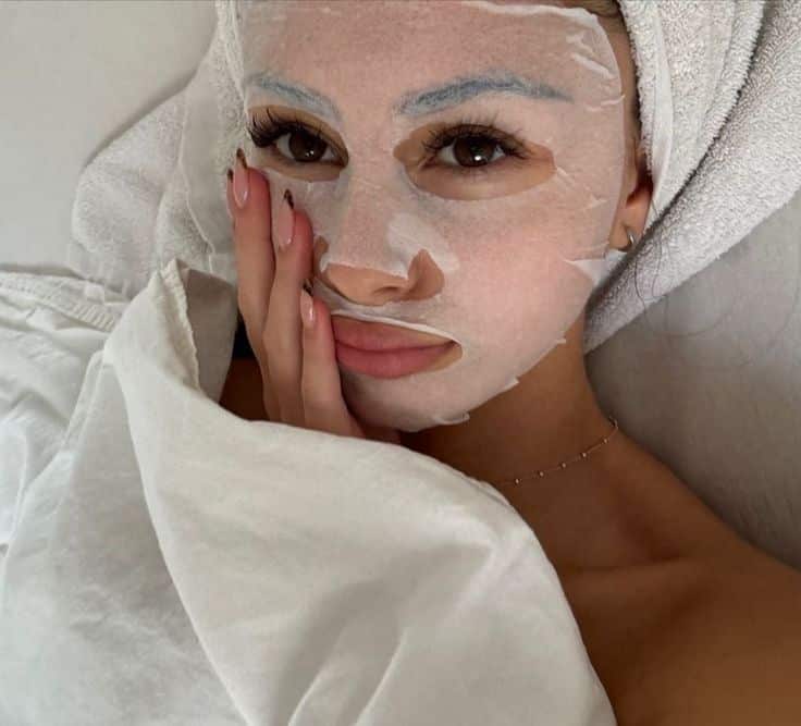 A woman’s face wearing a white sheet mask