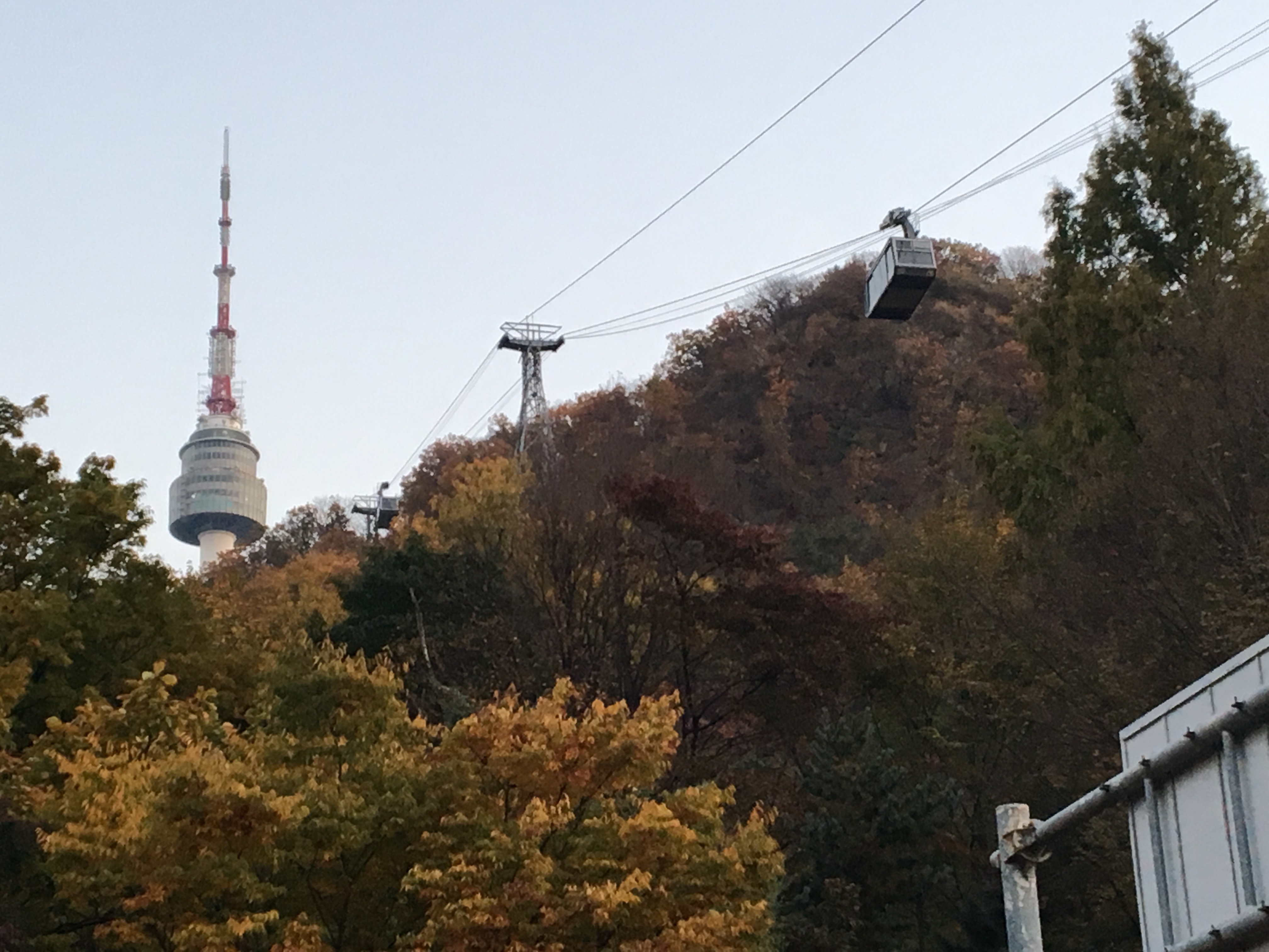 The cable car going up and down Namsan Ridge and in the background NA photo featuring Seoul Tower.