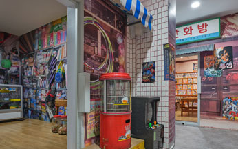 This is the scene of an old Seoul alley recreated behind the detention cell exhibition room, featuring an electronics repair shop and a comic book room..