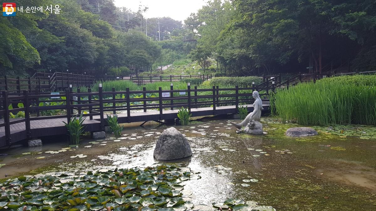 The deck and mermaid sculpture in the wetland garden of Achasan Oullim Garden can be seen..