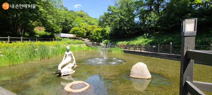 This is a view of the mermaid sculpture and walking deck in the wetland garden of Achasan Ecological Park..