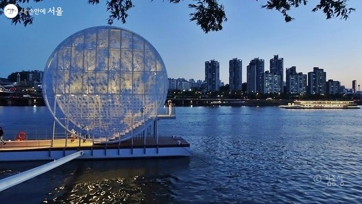This shows the Moonlight Nodeul artwork installed against the backdrop of the Hangang River surface and the city night view..