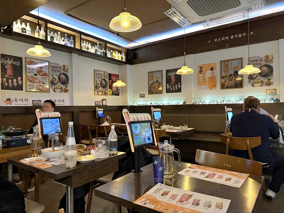 This is an interior view showing the table seating and a display of traditional liquor bottles at Uirak Mangwon Main Branch..