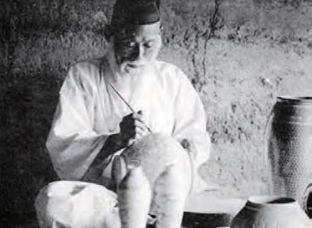 This is an archival photograph showing a potter from the late Joseon period painting on ceramics..