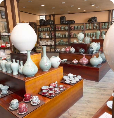 This shows white porcelain, celadon, and teacup sets displayed in a workshop shop at Sagimakgol Doyechon..