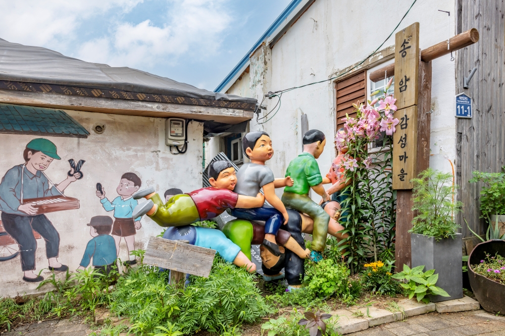 The mural in an alley of Daryong Market and 1970This is a scene featuring sculptures recreating everyday life from past decades..