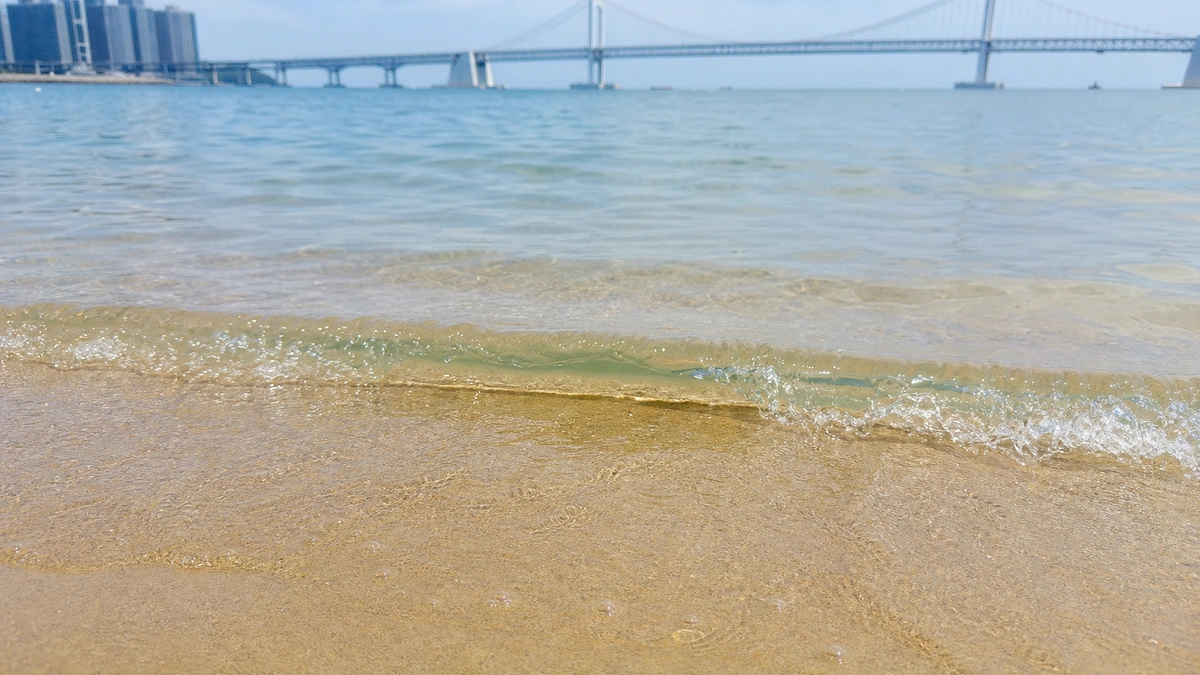 광안리해수욕장 모래사장에 잔잔한 파도가 들어옵니다.