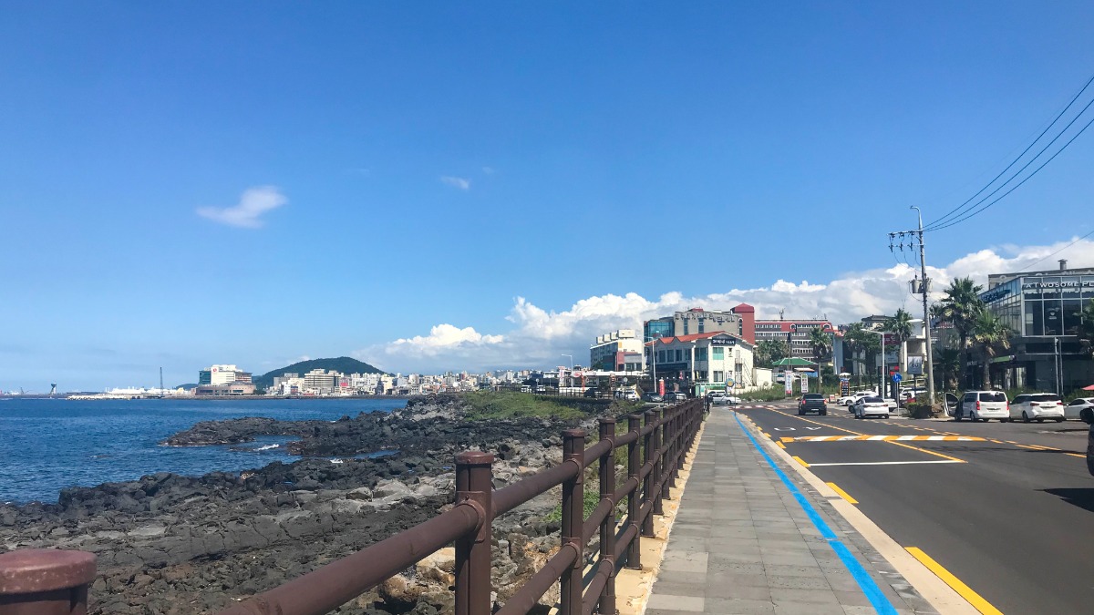 울타리 너머 돌 해변이 보이는 용두암해안도로 보행로 사진입니다.