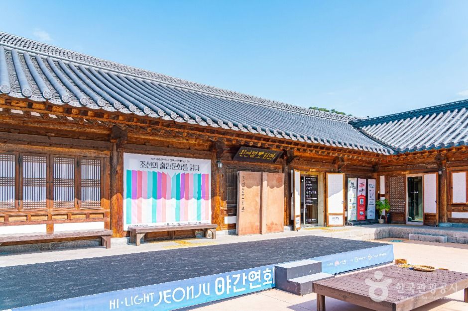 완판본문화관 전시실에서 완판본과 목판 자료를 살펴보는 모습입니다.