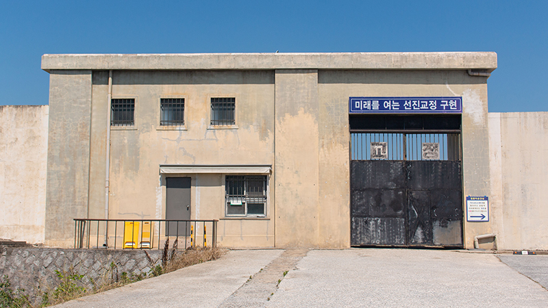 회색 담장과 철문이 있는 익산 교도소 세트장 정문입니다.