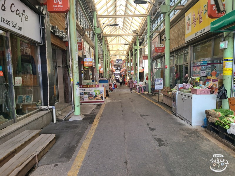 신정시장 상점가에서 장을 보는 일상적인 풍경을 담은 사진입니다.