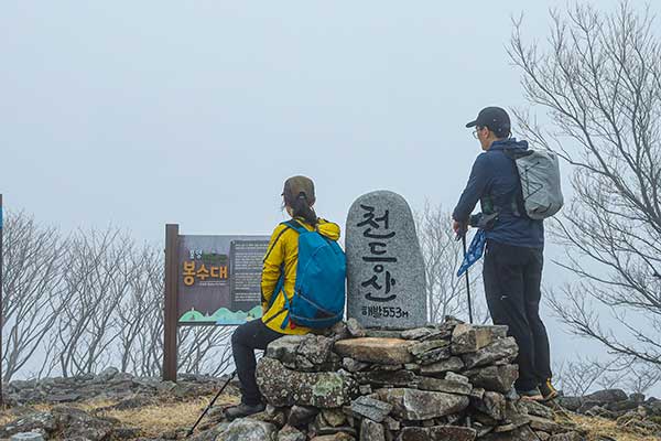 천등산 정상에서 주변 능선과 바다를 바라보는 장면입니다.